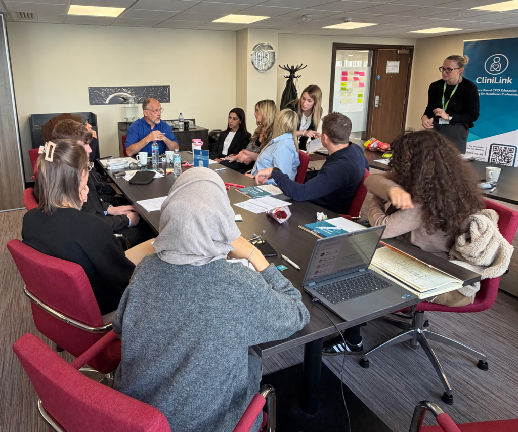 Delegates and a tutor discussing clinical skills around a table at a previous CliniLink workshop